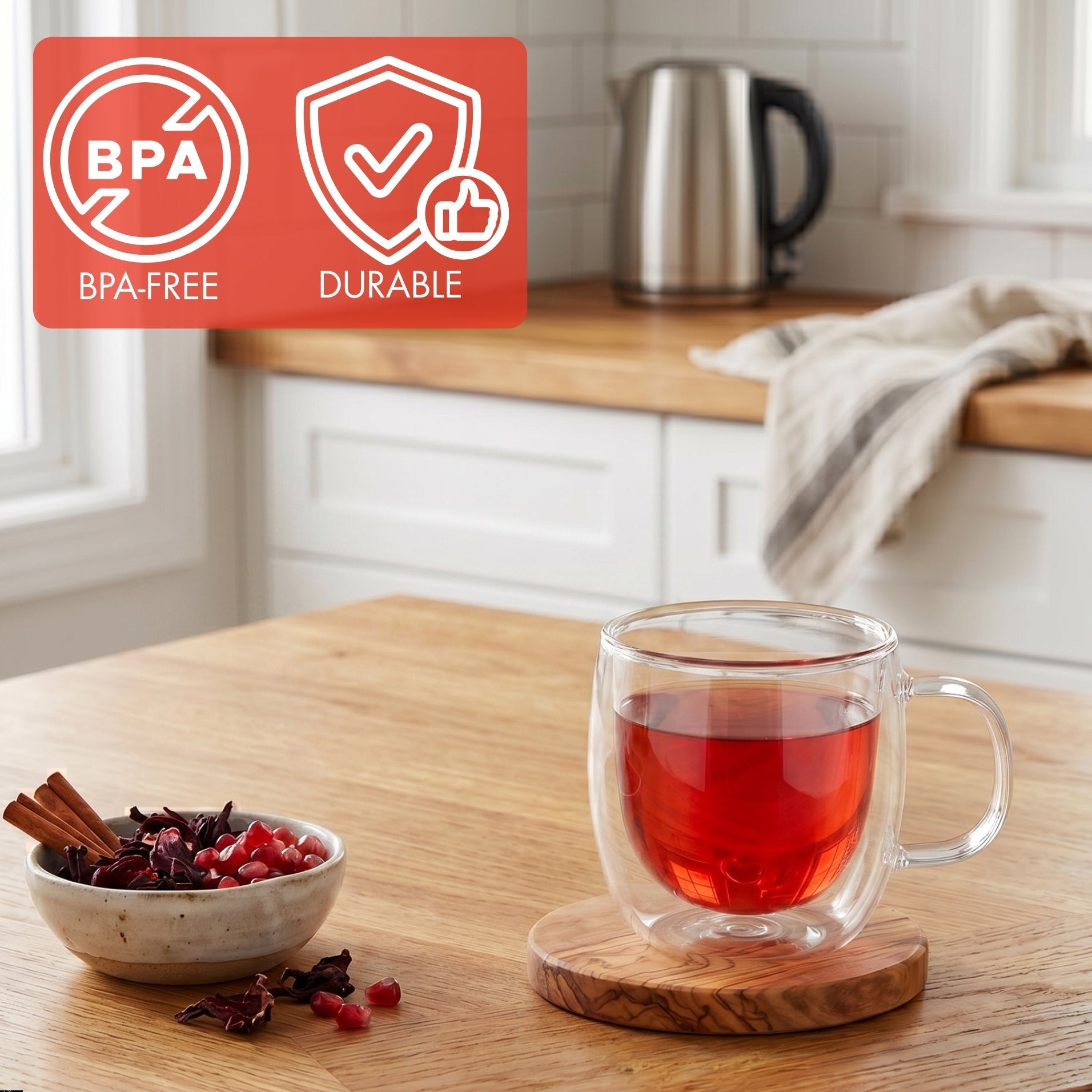 Clear glass mug with red liquid on a wooden coaster, bowl of spices, and kettle in the background.