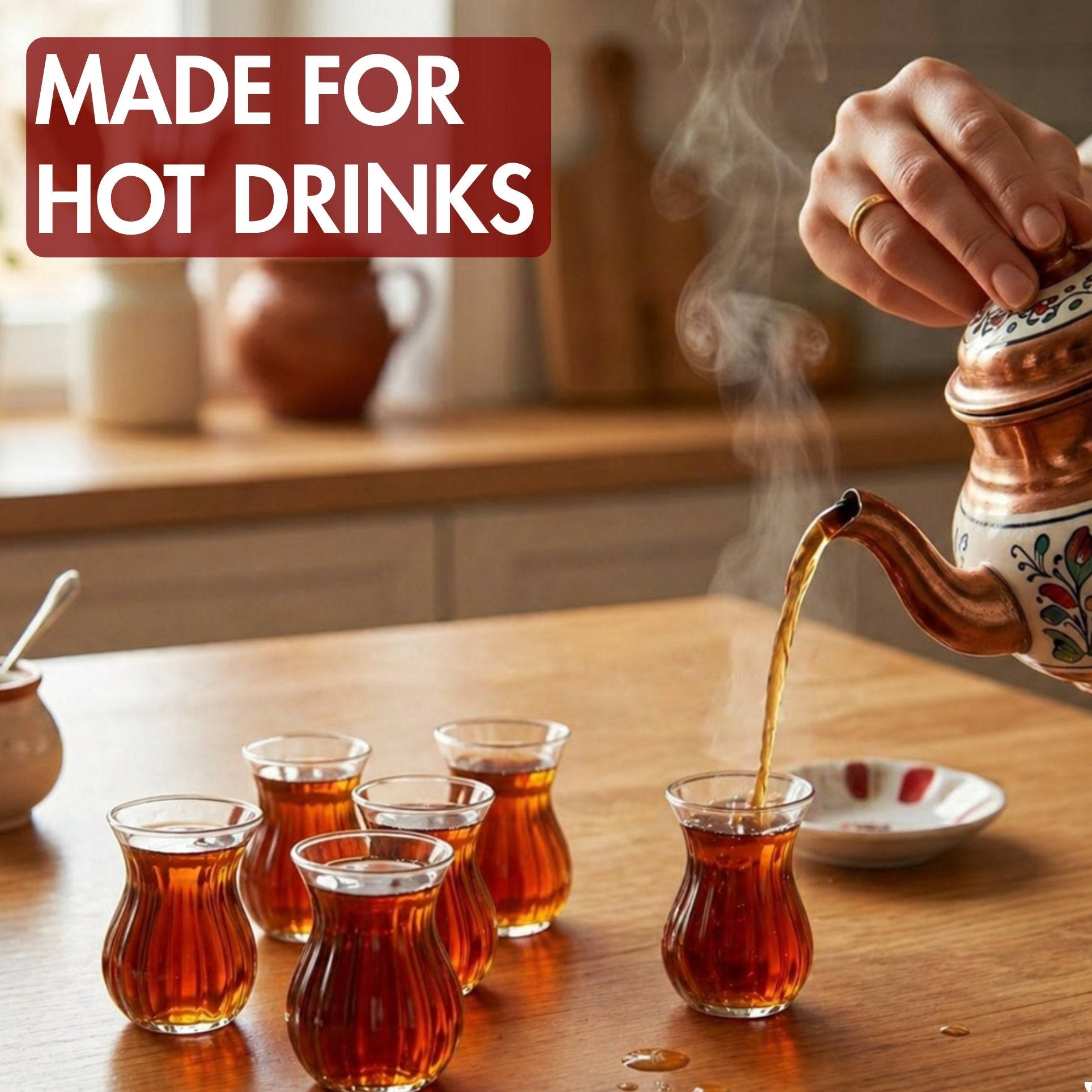 Tea being poured from a decorative teapot into small glasses on a wooden table.