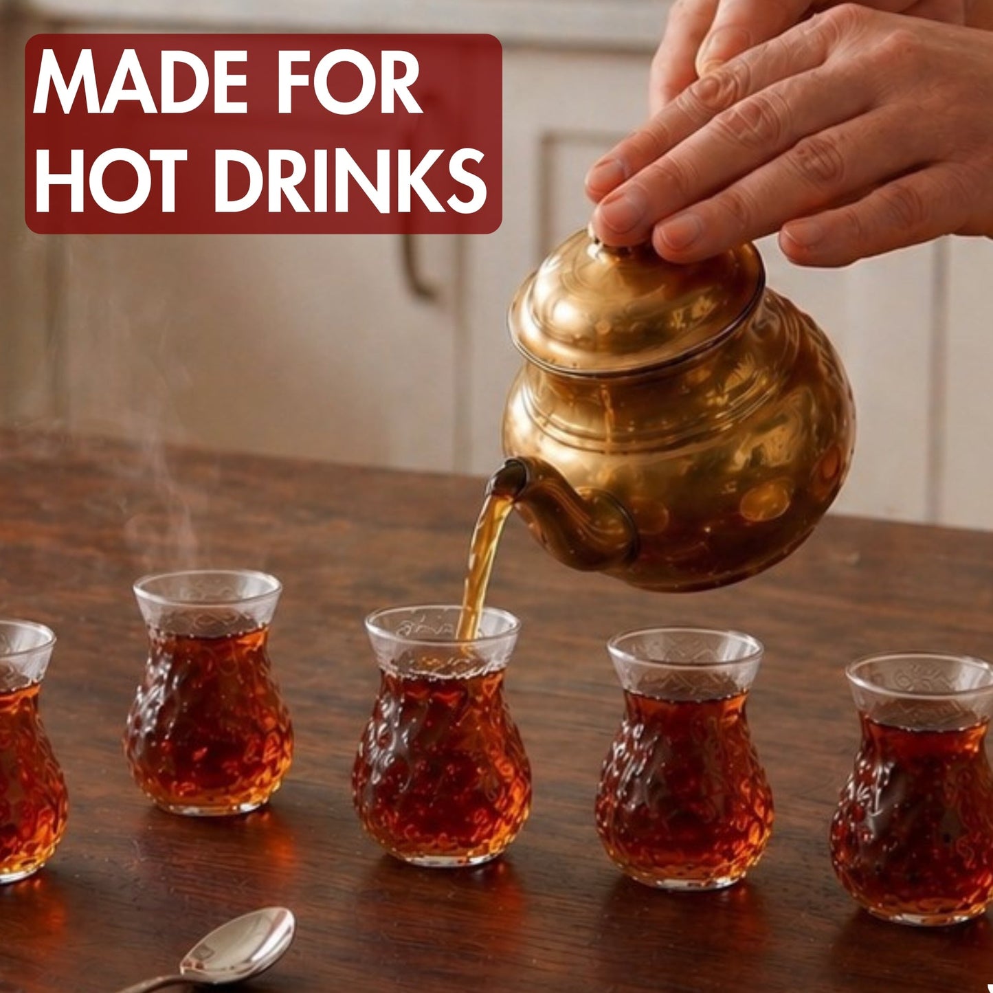 Tea being poured from a gold teapot into small glass cups on a wooden table.