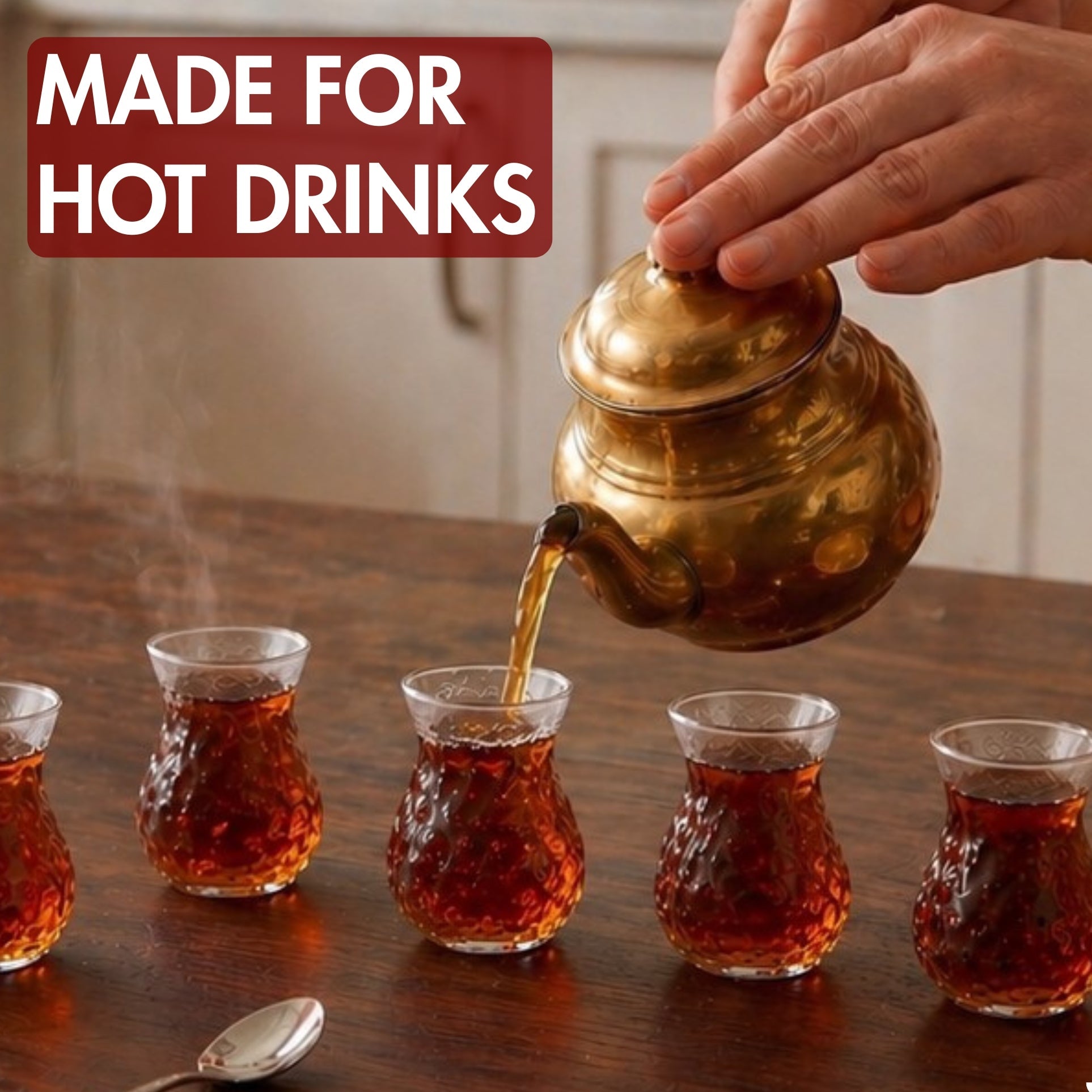 Tea being poured from a gold teapot into small glass cups on a wooden table.
