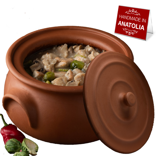 Terracotta pot with food inside, surrounded by vegetables and a 'Handmade in Anatolia' sign.