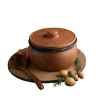 Terracotta pot with lid on a wooden board with potatoes and rosemary, 'Handmade in Anatolia' label.